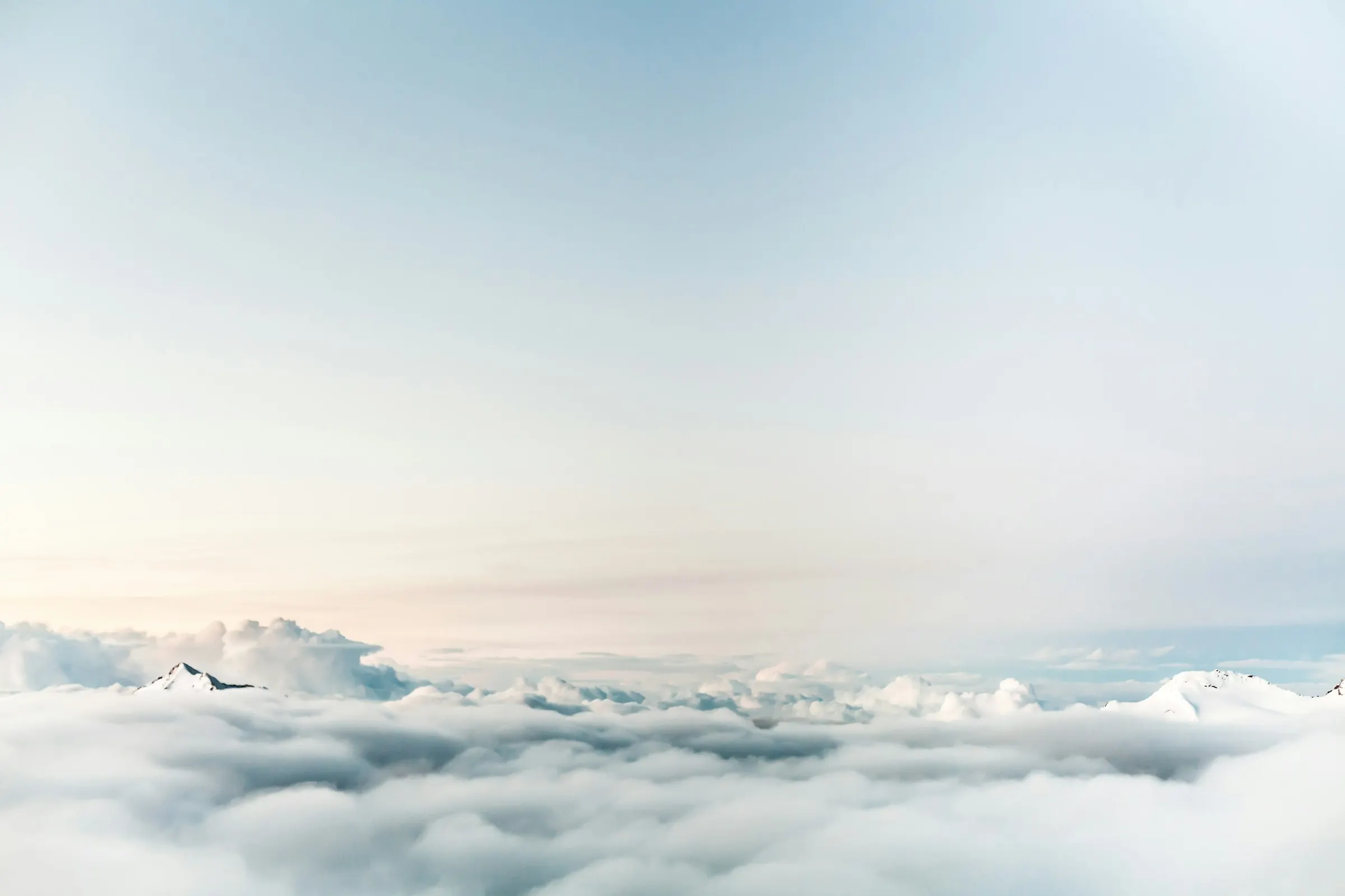 Au-dessus d’une mer de nuages, au lever du jour, la lumière pâle du matin.